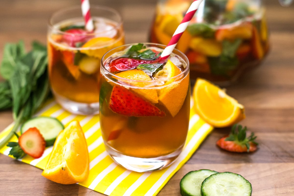 A cup of Pimm's with orange, cucumber and strawberries.