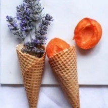 two waffle cones one filled with lavender the other with cut apricots