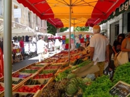 vendor standing at market with long row of produce in baskets