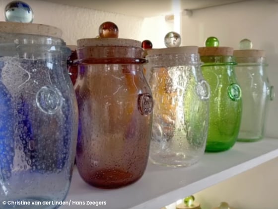 coloured glass jars with cork lids lined up on a shelf