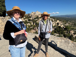 two women tourists standing on a hill with a hilltop village in the background