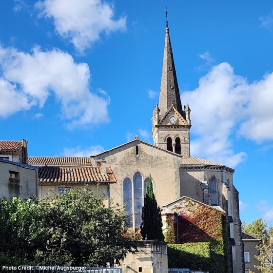 church and tall steeple against blue sky with a few clouds