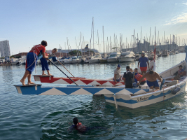 people swimming and playing on a wooden boat near a harbour