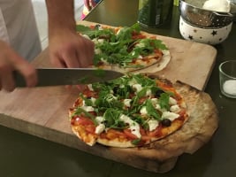 a person's hands holding a knife chopping ingredients onto a pizza