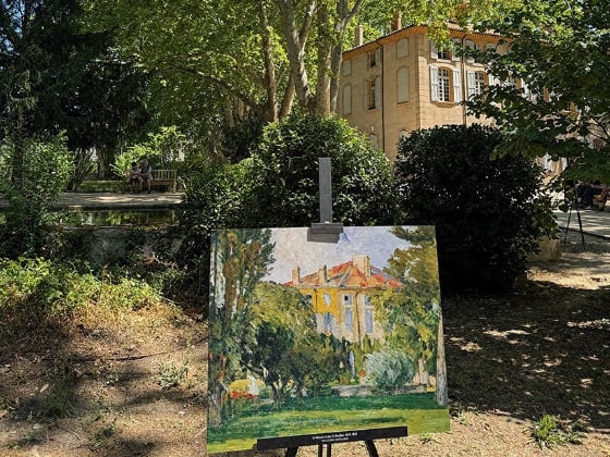 a painting of a house on an easel with the house in the background