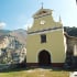 small chapel with blue sky, forest, and hills in the background