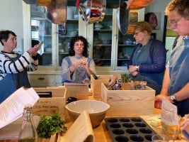 people in a kitchen looking at ingredients at a table learning to cook