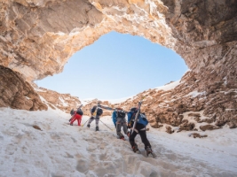 skiers with backpacks hiking up a mountain