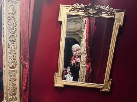 person taking a picture in a mirror on the wall covered in red velvet curtains
