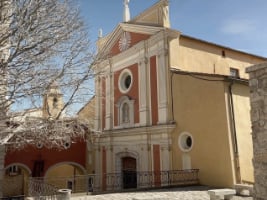 orangey-pink concrete church with white pillars on the front beside the door