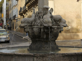 stone fountain of fish on a pedestal with water coming out of their mouthes into the basin