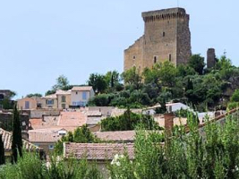 large stone castle on a hilltop with village sprawling down the hillside