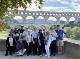 group of people standing with old stone bridge in background
