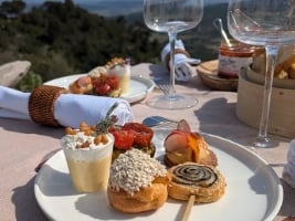 gourmet picnic foods on a plate with wine glasses in the background