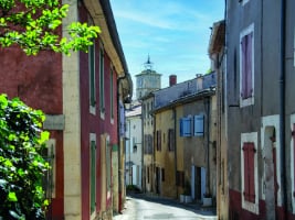 two story stone buildings with shuttered windows on either side of a narrow street