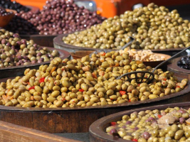 barrels full of olives with a laddle sitting on one barrel