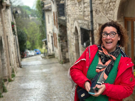 woman in red jacket standing on narrow street lined with stone buildings