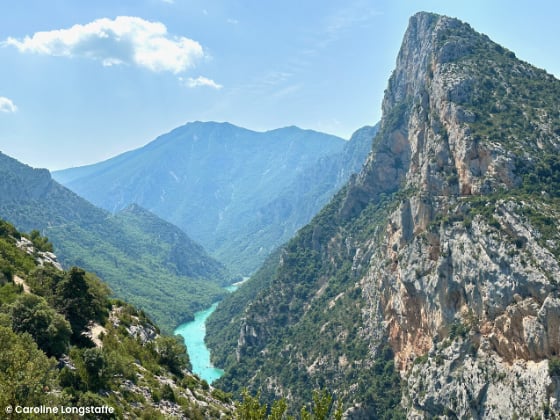 tall rocky mountains on either side of a bright blue river running through the valley
