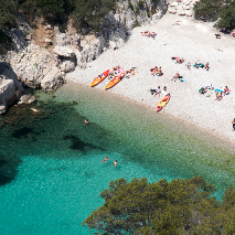 high aerial view of sandy beach with people and kayaks on the shore