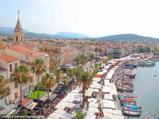 aerial view of markets on a city street between the buildings and harbour full of sailboats