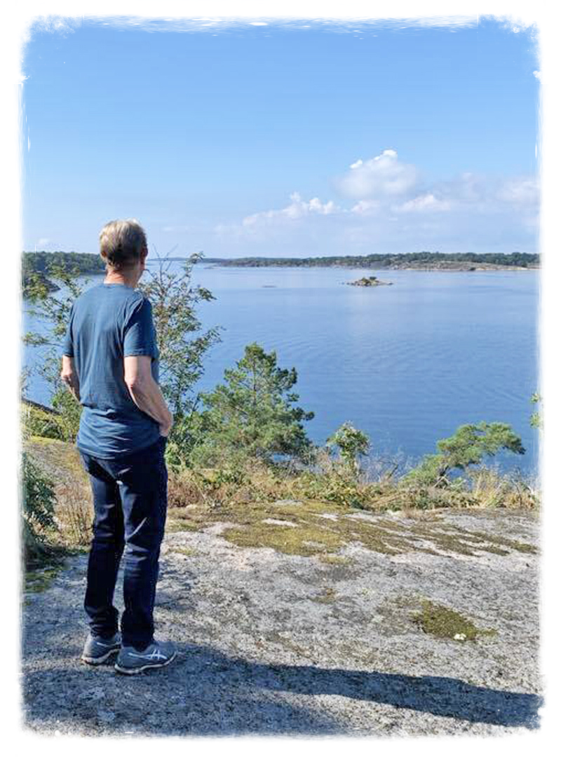 En man står lugn och trygg på en klippa och blickar ut över havet. En rofylld bild.