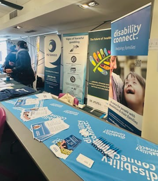 Information booth at an event featuring several display banners, including one for Disability Connect with the tagline 
