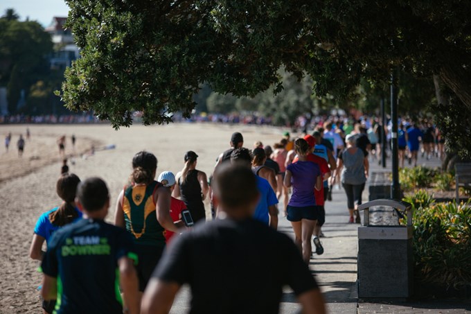 People running in a line along a beach boardwalk.