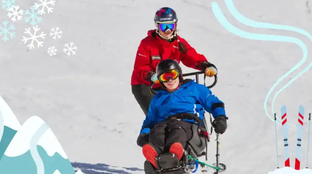 A person in a wheelchair is being assisted down a snowy slope by a guide, both wearing winter gear and helmets. Snowflakes decorate the scene.