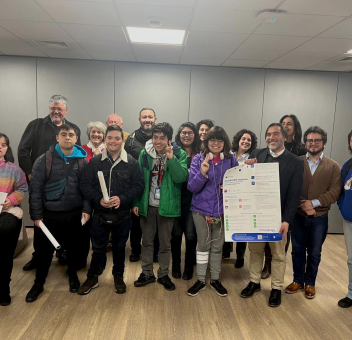 imagen en la que se precia a un grupo de personas mirando hacía la cámara con un póster de accesibilidad cognitiva.