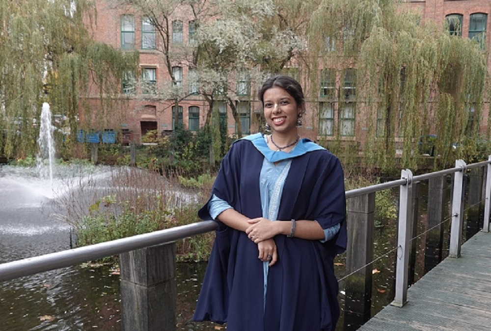 Krishangi Meshram standing in a graduation gown outdoors