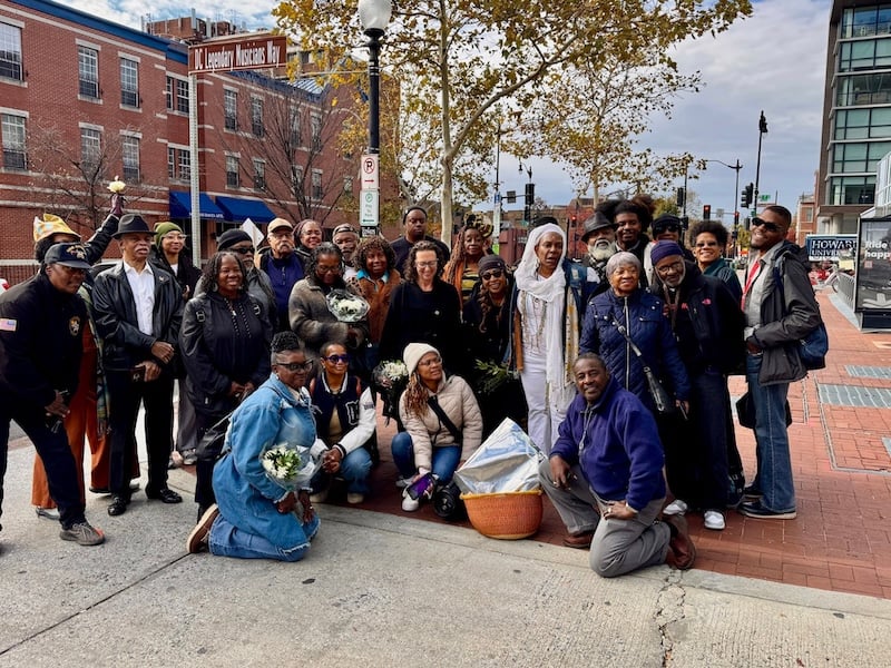 A group of people gathered under the “DC Legendary Musicians Way” street sign