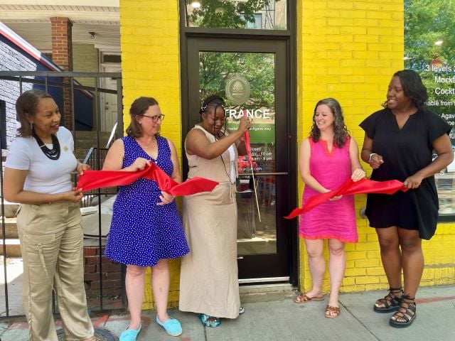 Councilmember Nadeau, Chef Kay, and other participants hold the ribbon for the official ribbon cutting of Omari Music Bar and Agave Lounge