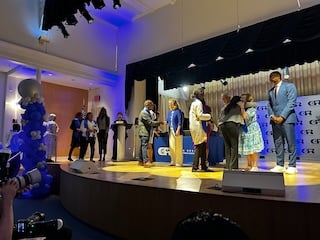 Graduates walk across the stage to receive their diploma