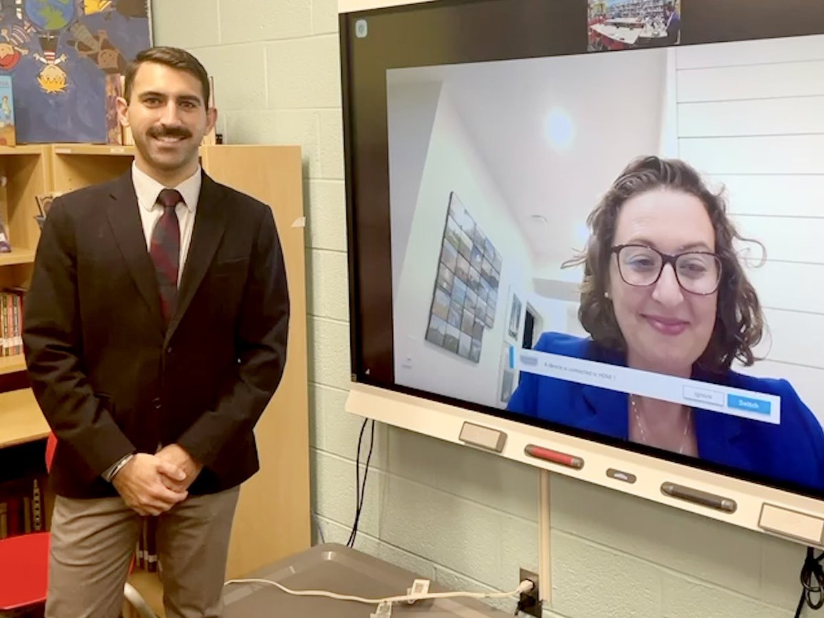 Jaspal Bhatia, in jacket and tie, standing, is sworn in by Councilmember Nadeau, who appears remotely on a large screen.