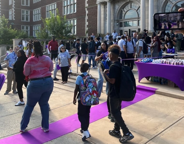 A purple carpet is laid out in front of a school as students enter