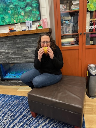 Councilmember Nadeau smiles while biting into an apple
