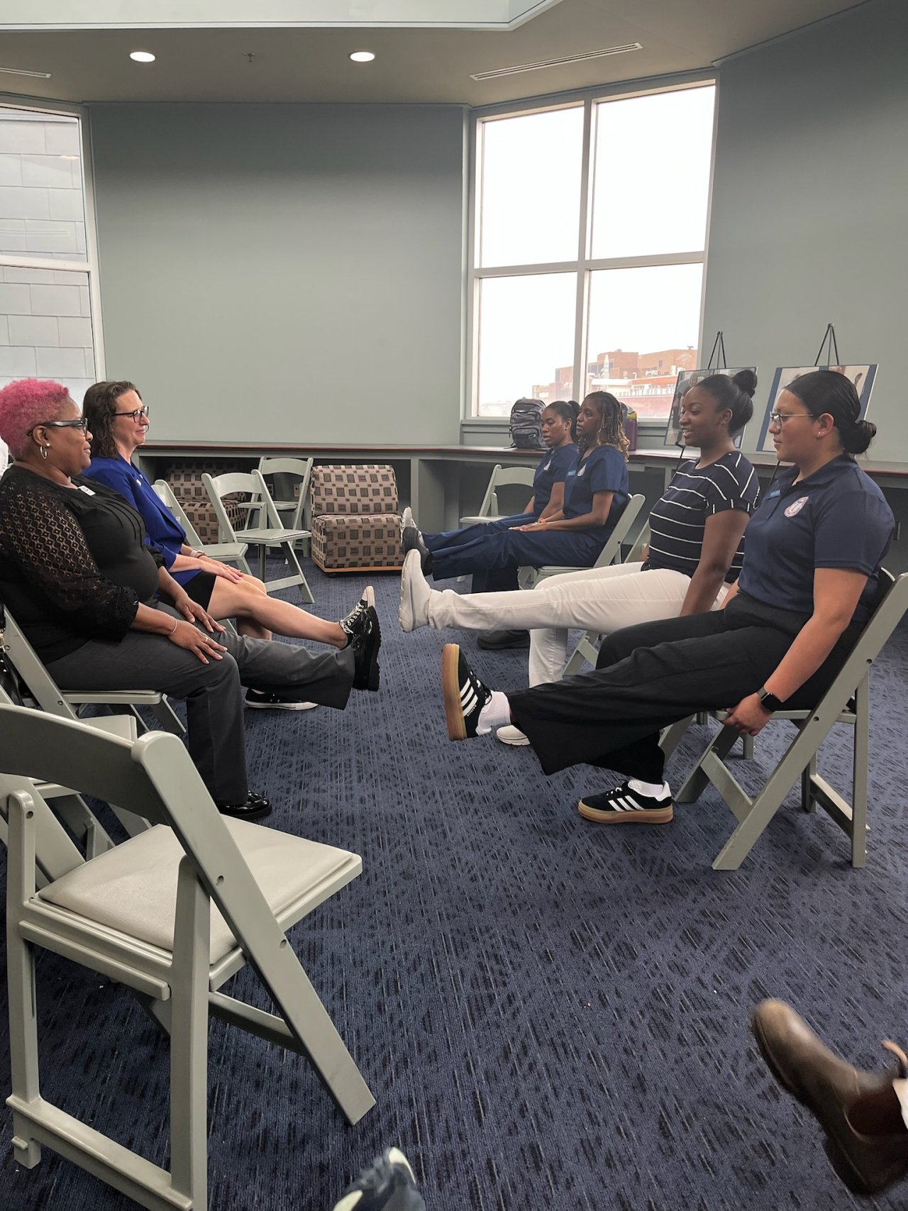 Several women, including Councilmember Nadeau, seated in chairs doing leg raise exercises