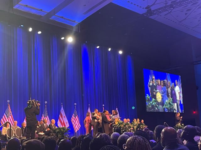 Wide shot of the stage at Washington Convention Center for swearing in ceremony. CM Janeese Lewis George is being sworn in and appears on jumbotron.