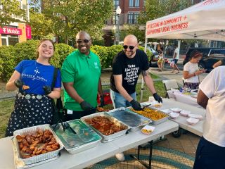 Community members serve food at Columbia Heights Juernes, including Estelle, wearing Brianne K Nadeau blue t-shirt