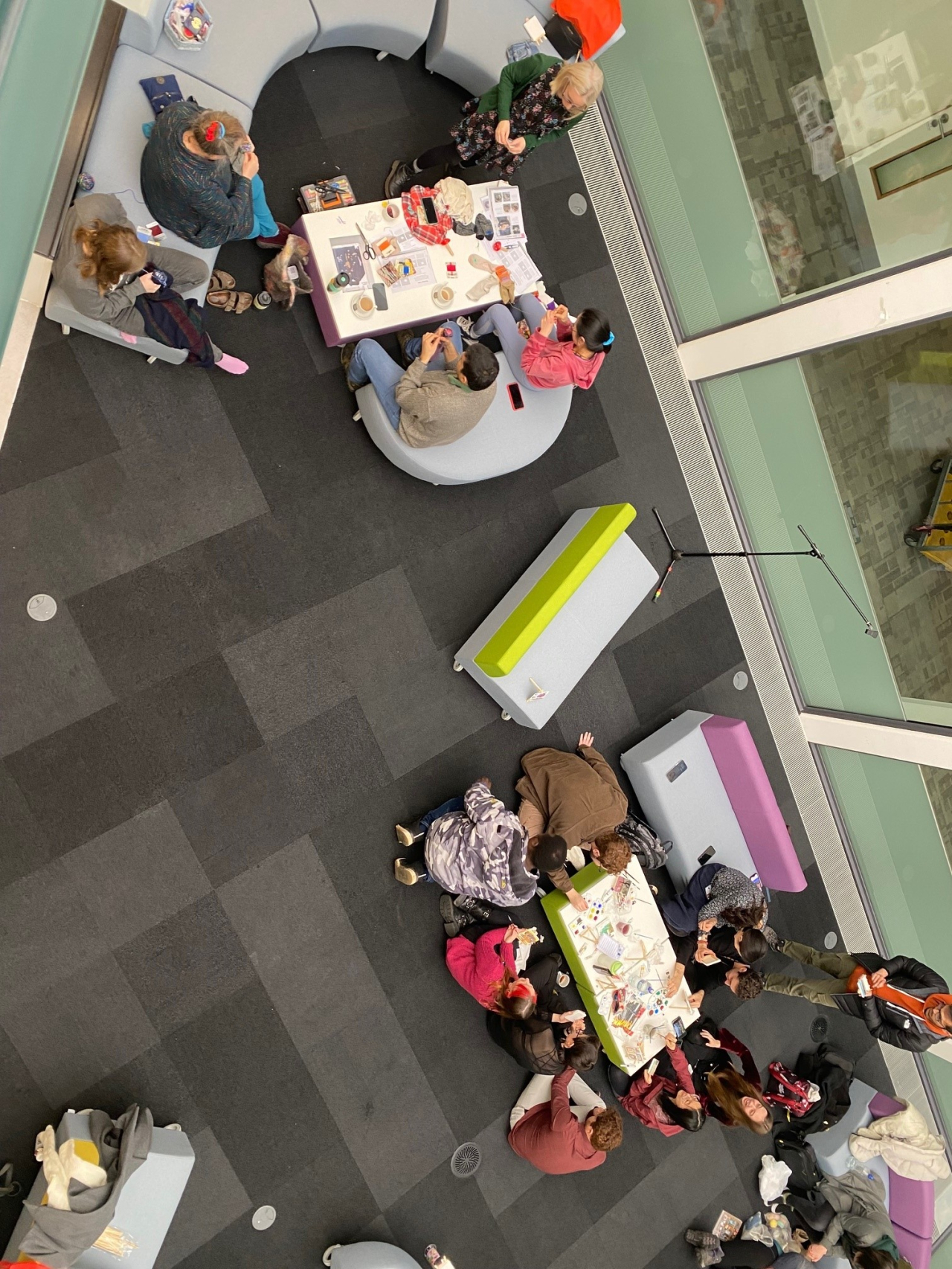 An aerial shot of people sitting around tables painting and sewing