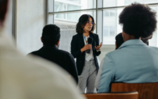 A person holding a microphone and facing an audience