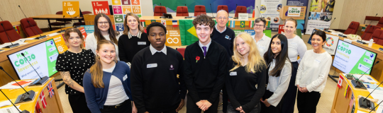 A group of school pupils in front of screens showing the words COP30.