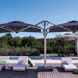 DUAL side-arm twin canopy umbrellas shown here in a poolside setting.