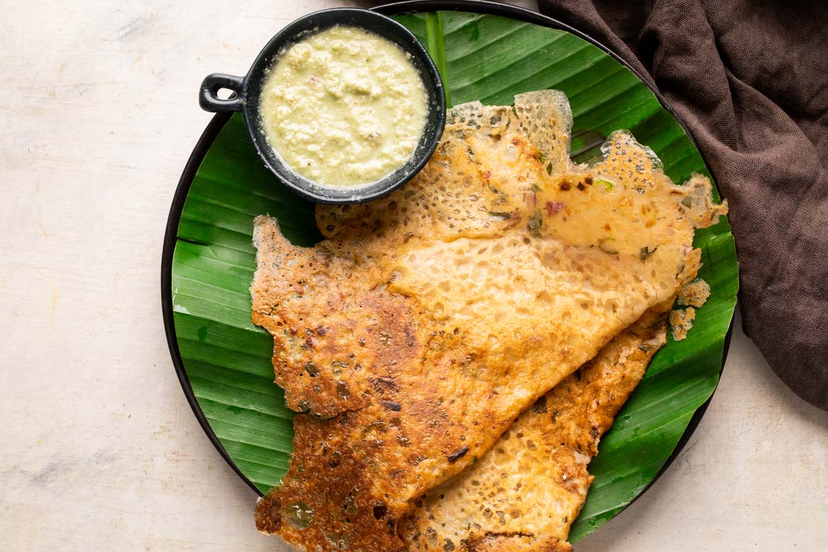 Oats dosa served on a banana leaf lined plate with coconut chutney