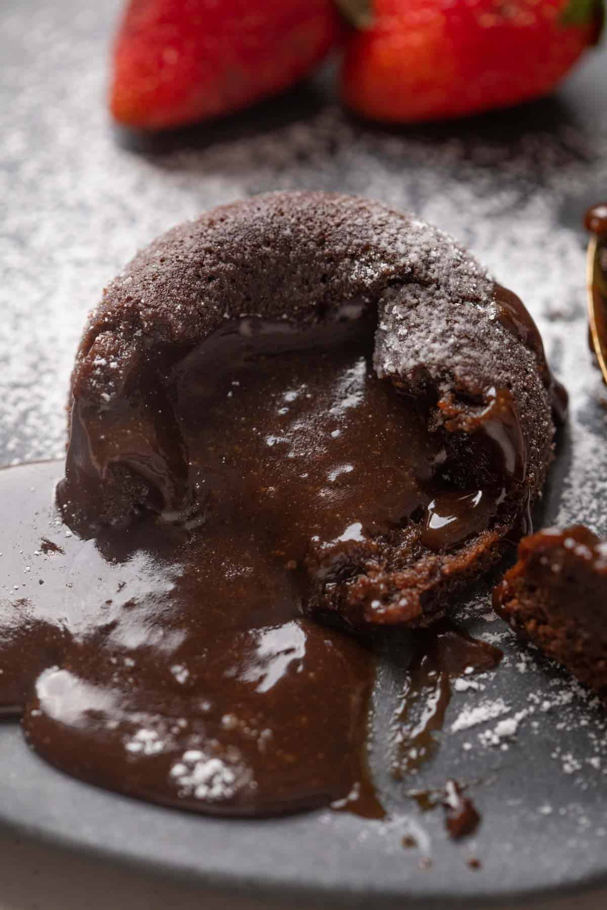 A plate with mocha lava cake with chocolate oozing out and dusted with icing sugar